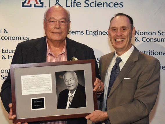 Picture of alumni and dean holding up award